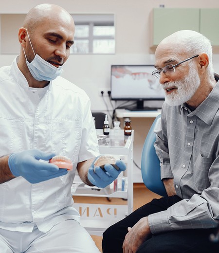 doctor showing dentures to patient